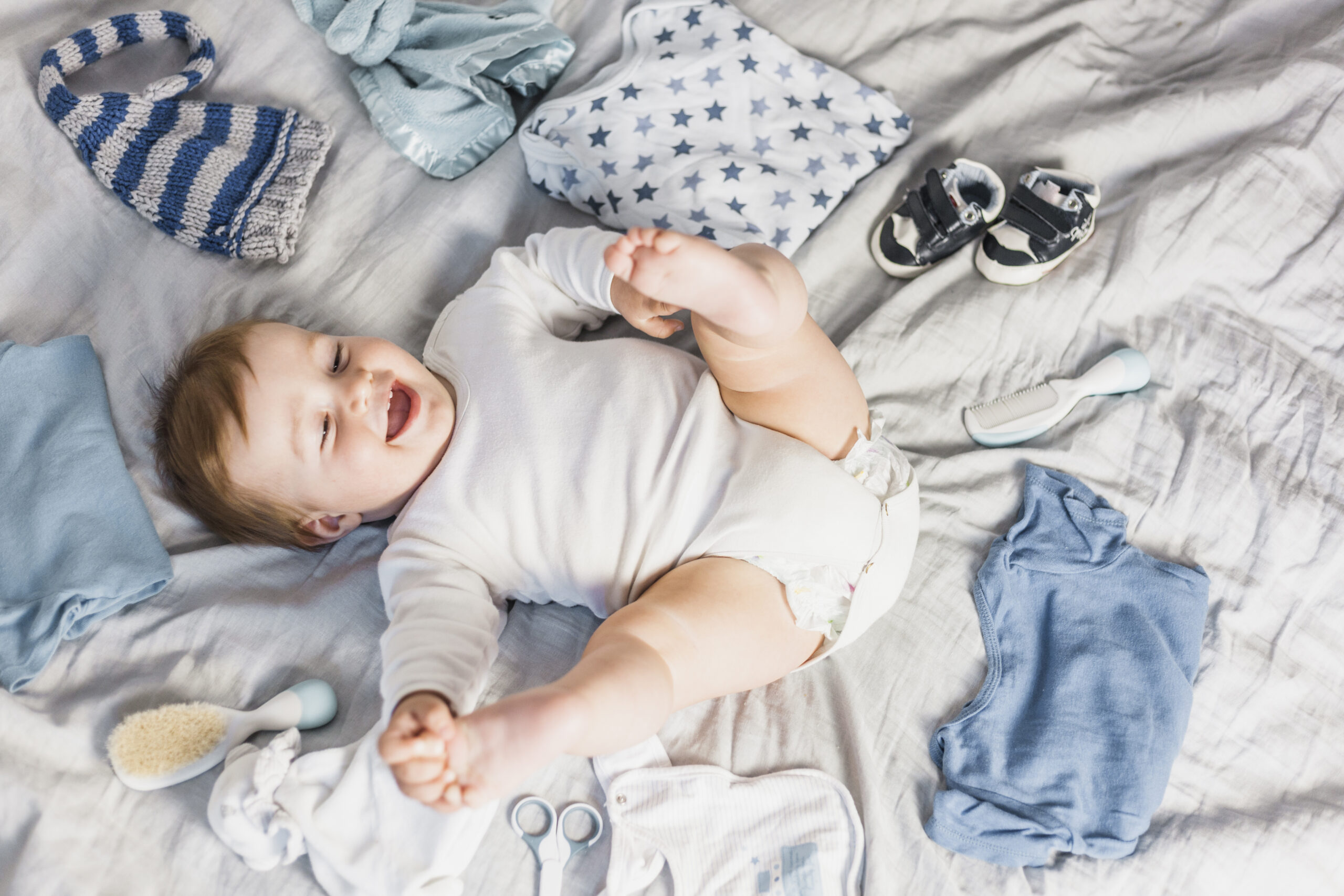 top-view-blonde-baby-surrounded-by-clothes